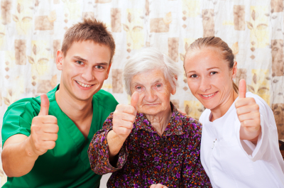 caregiver team thumbs up with old woman