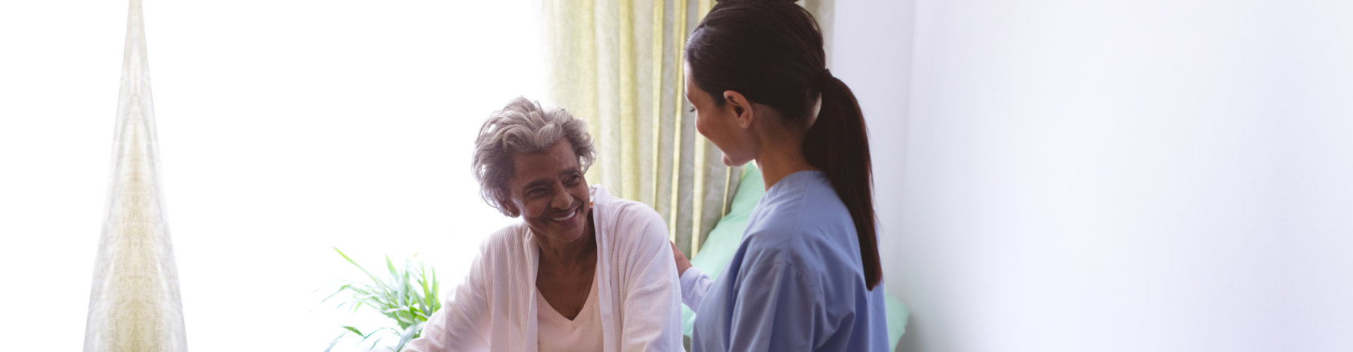old woman smiling while the caregiver supporting her